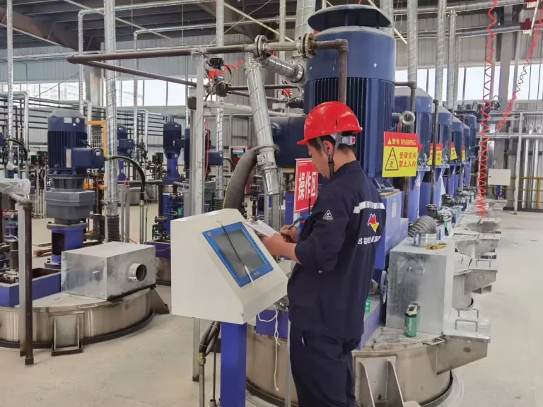 Paint factory operator checking production equipment inside a coating manufacturing workshop